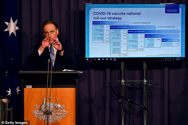 一个站在屏幕前的人：压力不断：卫生部长格雷格·亨特（Greg Hunt）向澳大利亚人保证，该国的疫苗接种计划正在逐步实施